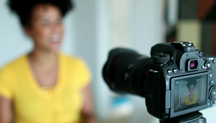 Woman in yellow shirt recording a customer testimonial with a DSLR camera to drive sales on Amazon.